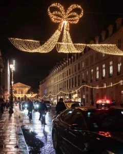 Christmas in Paris: a giant bow of lights strung across a rain-wet street at night