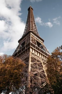 Eiffel Tower from below with autumn foliage and broken cloud