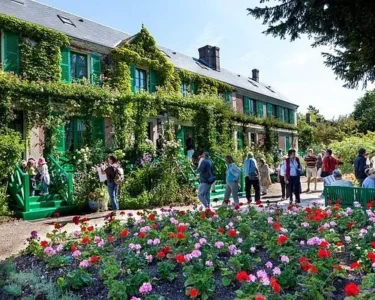 Visitors in front of Monet's ivy-covered house and flower beds at Giverny, a day trip from Paris