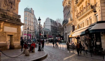 Cobbled Paris street lined with cafés and a lamp post on a quiet weekday